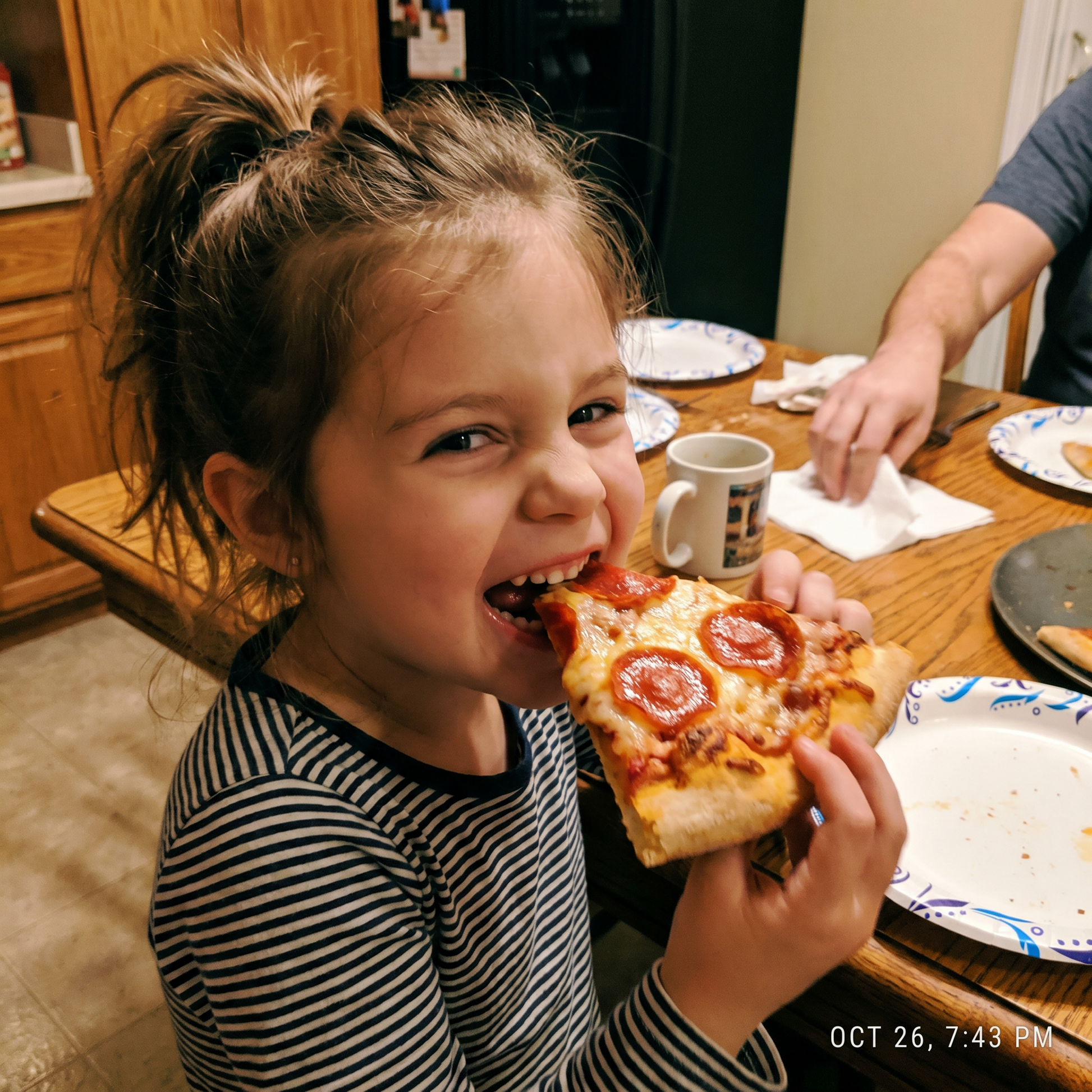 A child taking a big bite of home-made pepperoni pizza